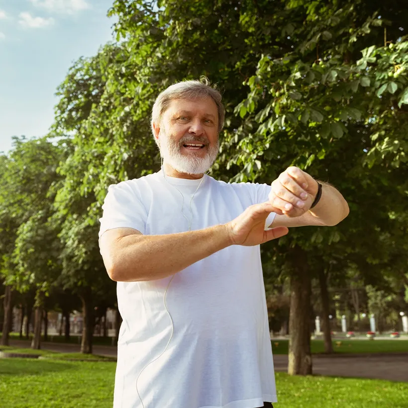An older man stretching outdoors in a park