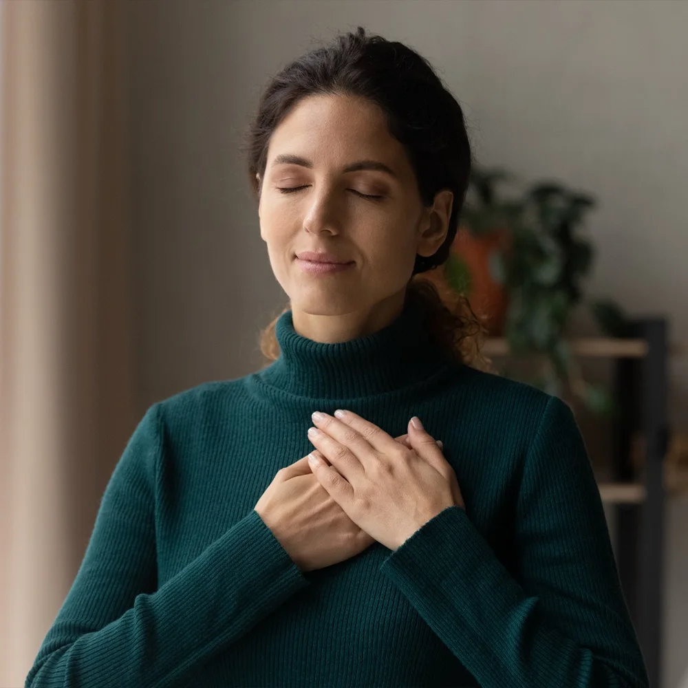 A woman with her eyes closed resting a hand on her chest