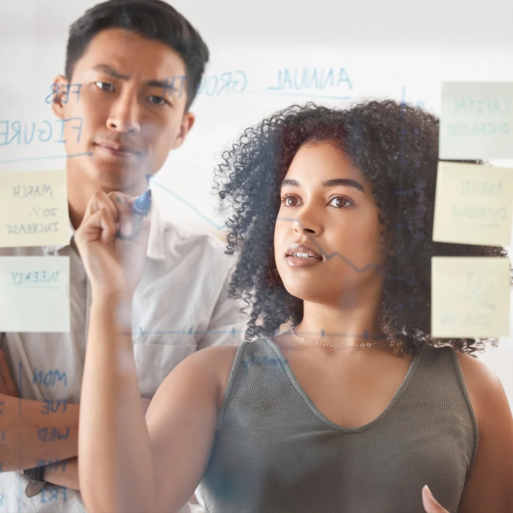 Colleagues working through notes on a glass whiteboard